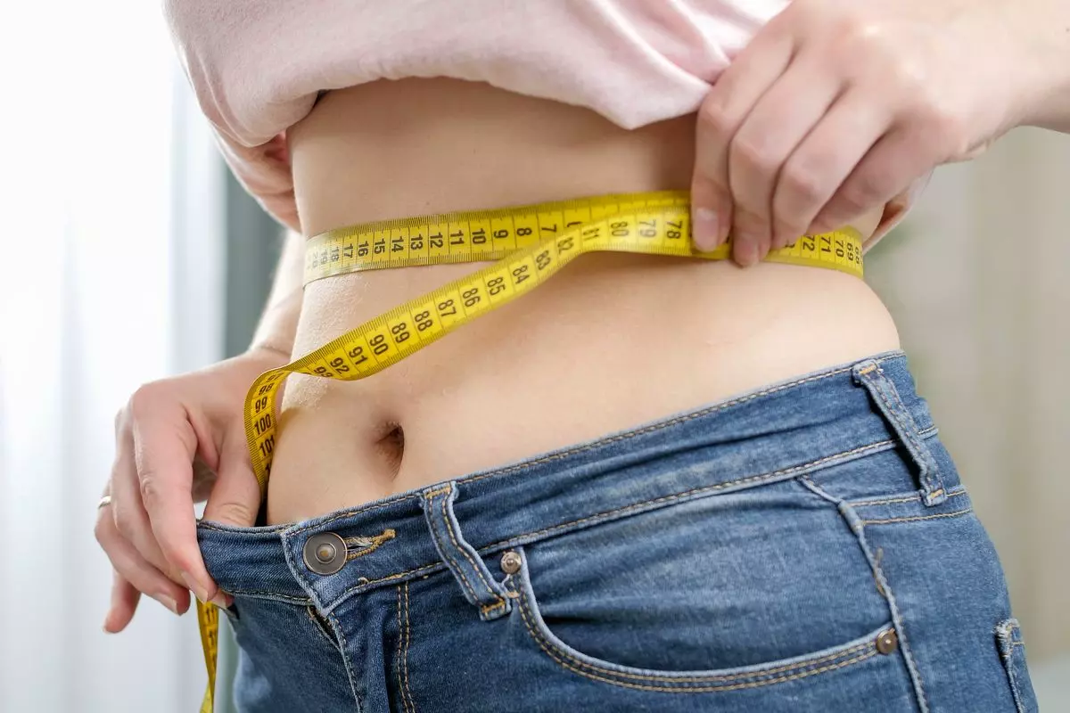 Femme se mesure le tour de taille après un régime